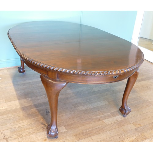 384 - An early 20th century mahogany wind out extending dining table with carved moulding, raised on cabri... 