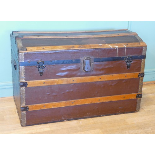 387 - An early 20th century dome topped twin handled trunk, with gilt brass mounts, the hinged lid opening... 