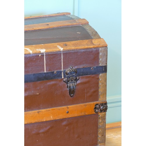 387 - An early 20th century dome topped twin handled trunk, with gilt brass mounts, the hinged lid opening... 