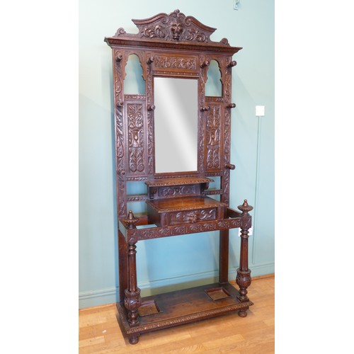 389 - A late 19th century heavily carved oak mirror back hallstand/coat stand, the frieze carved with the ... 