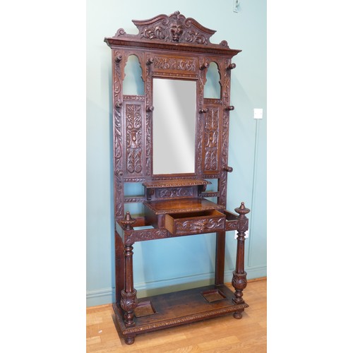 389 - A late 19th century heavily carved oak mirror back hallstand/coat stand, the frieze carved with the ... 