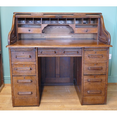 An early 20th century oak tambour twin pedestal writing desk, opening to reveal fitted interior, each pedestal with two shallow and a filing drawer, 120 x 115 x 76cm