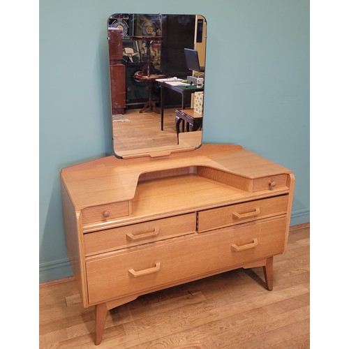 Ebenezer Gomme for G-Plan; a blonde elm mirror backed dressing table, with two small jewellery drawers above two short drawers and one long deep drawer raised on splayed supports, gold painted mark to interior of one drawer, 106cm wide.