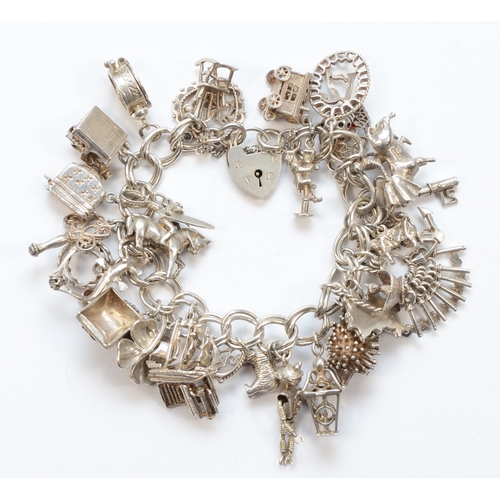 212 - A silver heart padlock clasp charm bracelet with charms, to include a toaster charm, 108gm.