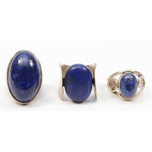 217 - Three Modernist lapis lazuli rings to include a over sized cabochon example,  K-L, 38gm.