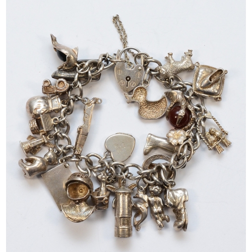 223 - A silver heart padlock clasp charm bracelet with charms, to include a ball and claw example, 87gm.