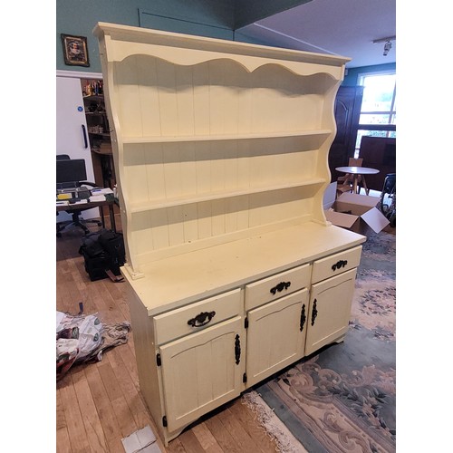 A painted pine kitchen dresser, the shaped top having two tier panelled plate rack over three frieze drawers with three cupboard doors opening to a central fitted shelf, raised on a shaped plinth base.
W140, D43, H184cm.