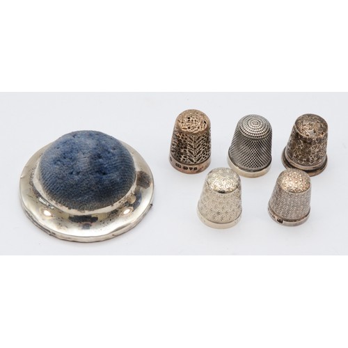 85 - A silver pin cushion, Birmingham 1906, four silver thimbles and a Sterling Silver example