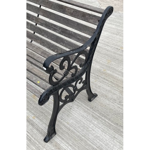 28 - A two seater garden bench, with slatted wood seat and combined back, raised on painted cast iron scr... 