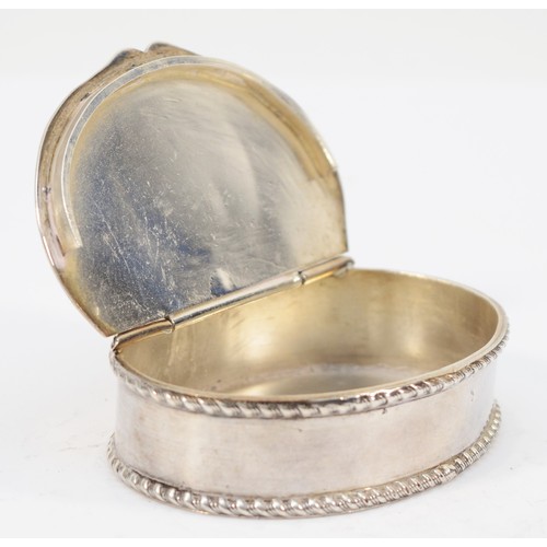 61 - An unmarked white metal oval snuff box, the hinged lid inset with a George IV coin, gadrooned border... 