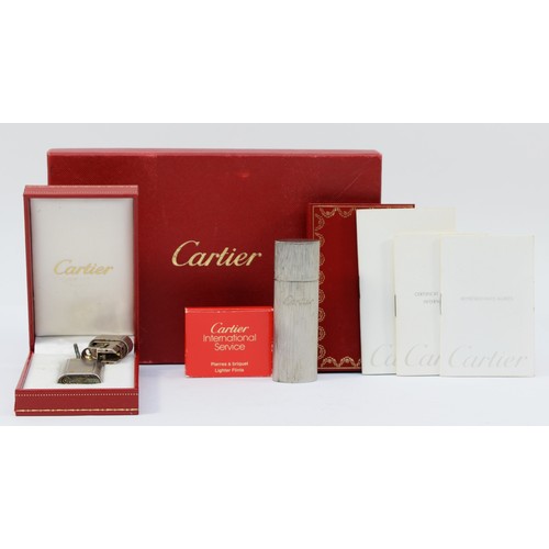 80 - Cartier, a brushed stainless steel and gold screw gas lighter, numbered E 72746, dismantled, case, w... 