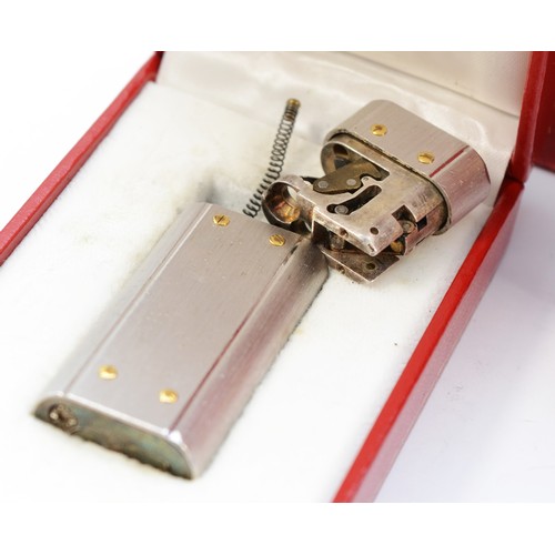 80 - Cartier, a brushed stainless steel and gold screw gas lighter, numbered E 72746, dismantled, case, w... 