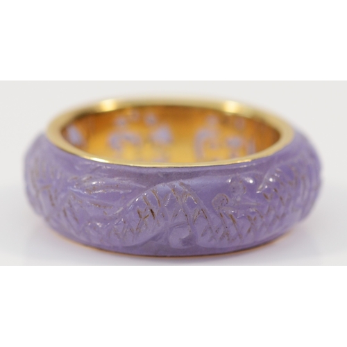 139 - A Chinese 14ct gold and enhanced carved lavender jadeite band ring, depicting two dragons chasing th... 