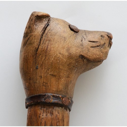 197 - A late 19th century carved fruitwood walking stick, the carved dogs head terminal with glass bead ey... 