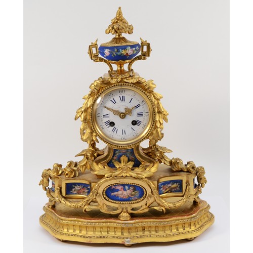 A French ormolu mounted Sèvres mantel clock, late 19th Century, of Louis XVI style, having 8 day striking movement by Japy Freres, the case of arched architectural form surmounted by a painted urn on shaped base, inset with painted porcelain panels depicting a cherub amongst sprays of flowers raised on a shaped giltwood plinth, 41cm tall.