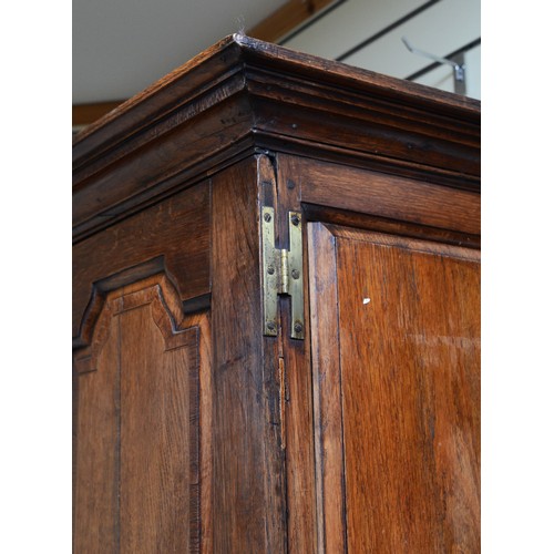 356 - A George III oak livery cupboard, projecting moulded cornice over two panelled doors, the upper pane... 