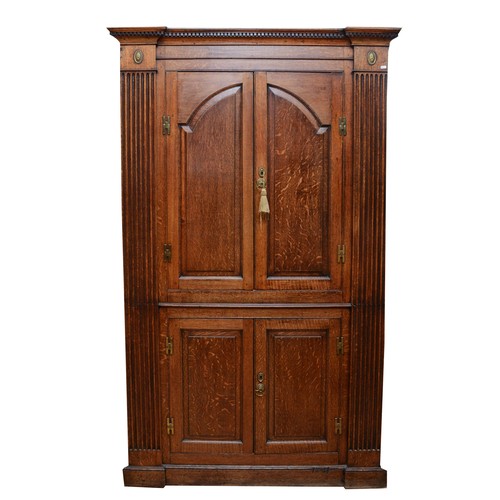 375 - A large George III oak corner cupboard, projecting cornice over two stepped arch doors with fielded ... 