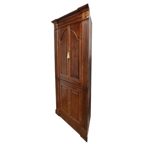 375 - A large George III oak corner cupboard, projecting cornice over two stepped arch doors with fielded ... 