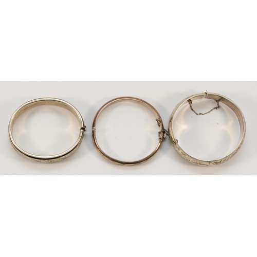 182 - A silver hinged bangle, Birmingham 1961, 60 x 48mm, 18mm wide, another Birmingham 1970, 9mm wide and... 