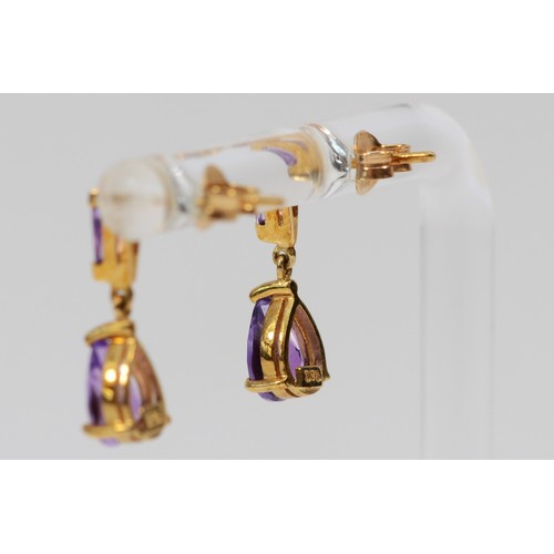 40 - A pair of 9ct gold pear cut and tapered baguette cut amethyst drop earrings, 15mm drop, with scroll ... 