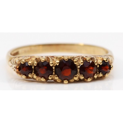 65 - A 9ct gold garnet five stone ring with a scroll patterned gallery, R, 2.4g