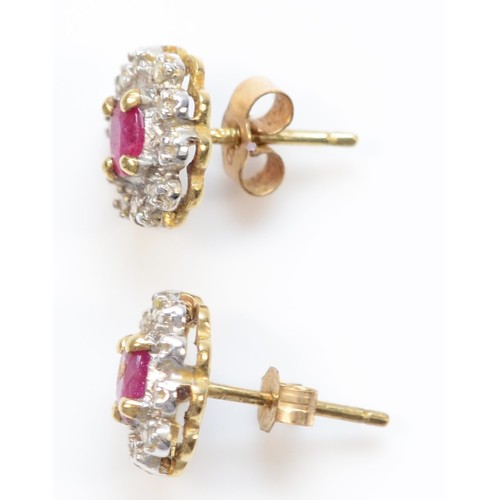 127 - A pair of 9ct gold oval cut ruby and diamond cluster earrings with scroll backs, 1.4g