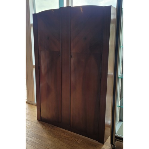 160 - A mid 20th century walnut veneered double wardrobe, the curved double doors opening to a fitted rail... 