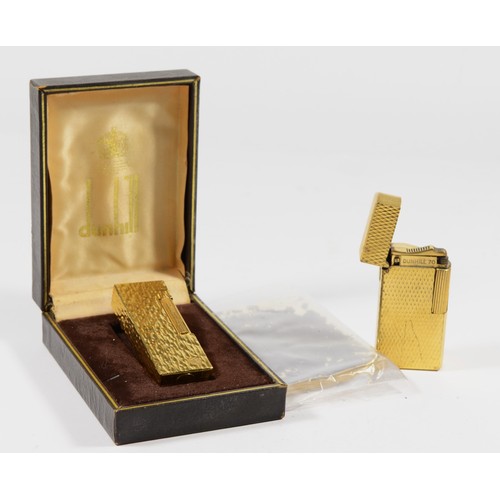 6 - Dunhill, a gold plated textured rollagas lighter, booklet and box and another by the same, serial nu... 