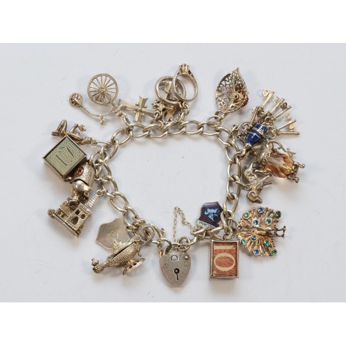 225 - A silver charm bracelet, including a £1 note and 10 Shilling note, 57gm