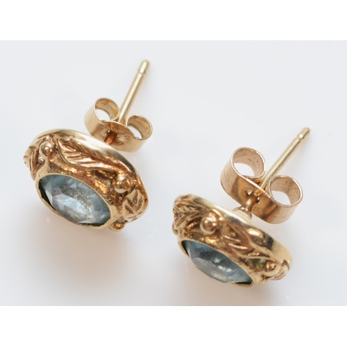 252 - A pair of 9ct gold aquamarine paste stud earrings with foliate patterned border, 2.3g