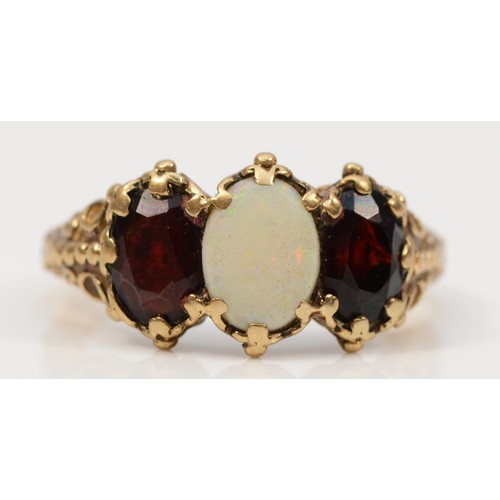 317 - A 9ct gold vintage opal and garnet three stone ring, with patterned shoulders, O 1/2, 2.9g