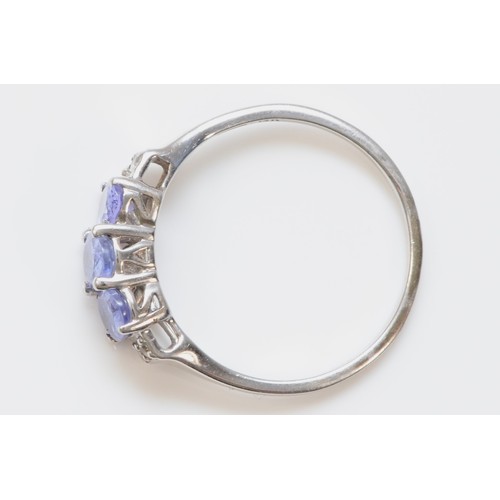 97 - A 9ct white gold oval cut tanzanite dress ring, three tanzanite stones, diamonds on the shoulders, S... 