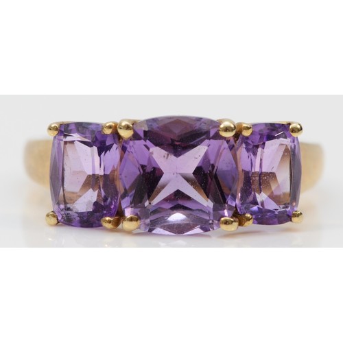 121 - A 9ct gold amethyst three stone ring, claw set with cross over detail to the gallery, Q, 3.2g