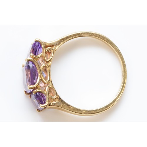 121 - A 9ct gold amethyst three stone ring, claw set with cross over detail to the gallery, Q, 3.2g