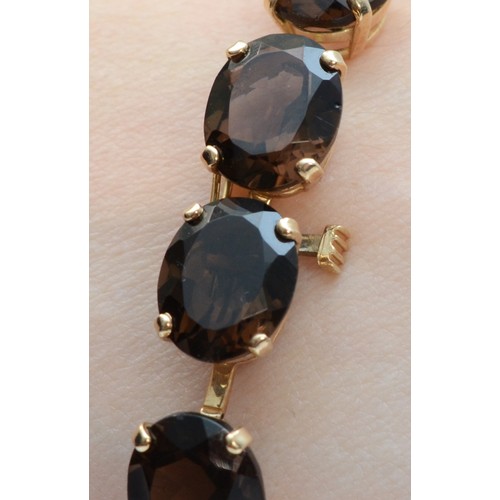 151 - A 9ct gold oval cut smokey quartz bracelet, 18cm, 15g