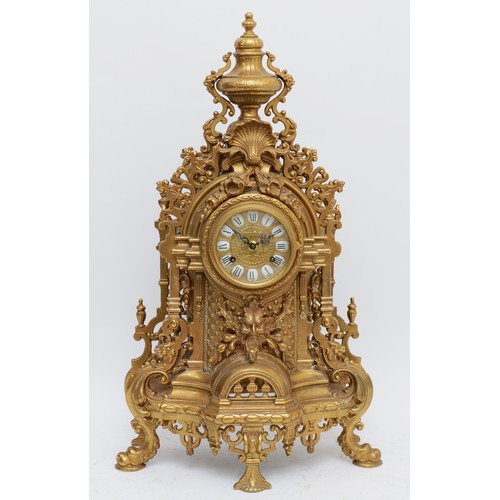 371 - A 20th century large and ornate brass mantel clock, with heavy floral case and vase surmount, the Ge... 