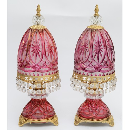 388 - A pair of ruby cut glass lamps, with gilt mounts and lustre drops, 41cm, together with a pair of cle... 