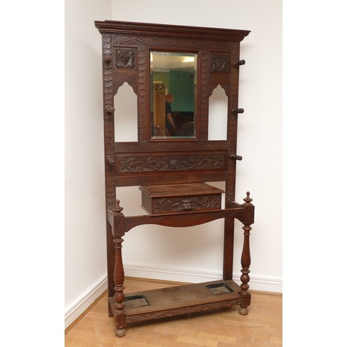 456 - An early 20th century Jacobean revival oak hall stand, the carved stepped pediment over rectangular ... 