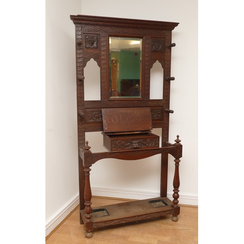 456 - An early 20th century Jacobean revival oak hall stand, the carved stepped pediment over rectangular ... 