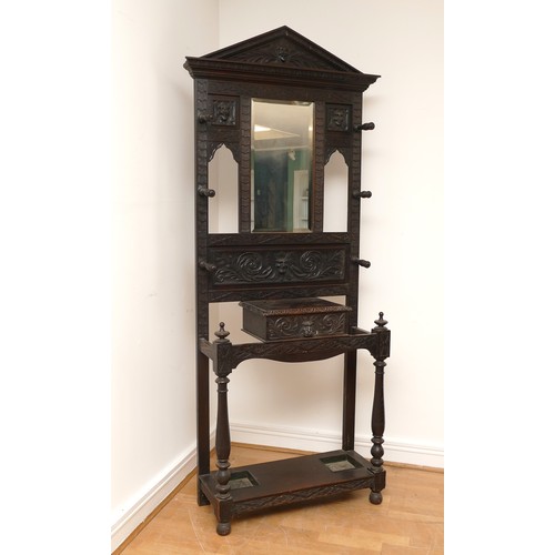 455 - A late 19th century Low Countries oak hall stand, with foliate and mask carvings, central bevelled e... 