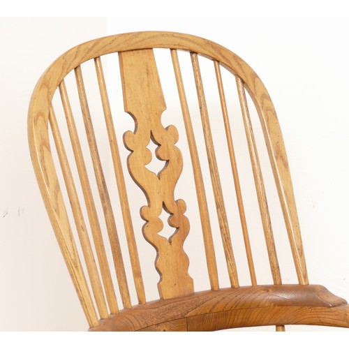 444 - An early 20th century beech and elm high back windsor armchair, the hooped backrest with pierced spl... 