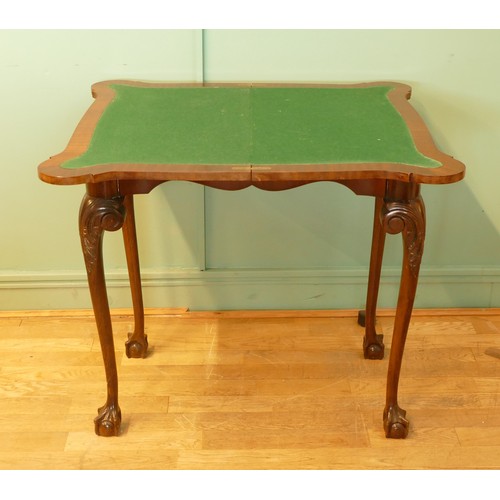 449 - An Edwardian mahogany fold over games table, with baize cover and leaf capped with ball and claw fee... 