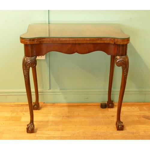 449 - An Edwardian mahogany fold over games table, with baize cover and leaf capped with ball and claw fee... 