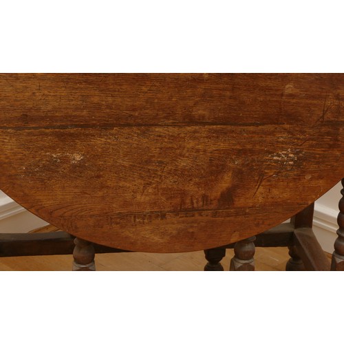 463 - A late 18th century oak gateleg dining table, the extending planked top of oval form, raised on turn... 