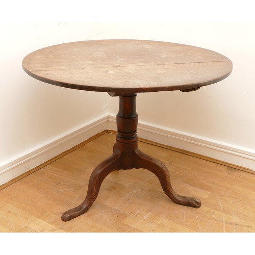 472 - A 19th century oak circular tilt top table, on a turned pedestal with outswept shaped supports, 93cm... 