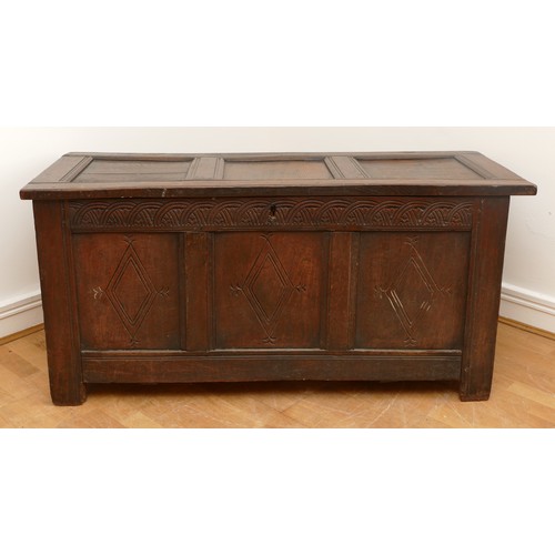 476 - A 17th century oak coffer, the hinged three panel top, above a guilloche frieze and two lozenge carv... 