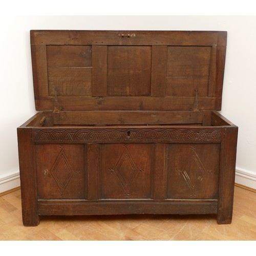 476 - A 17th century oak coffer, the hinged three panel top, above a guilloche frieze and two lozenge carv... 