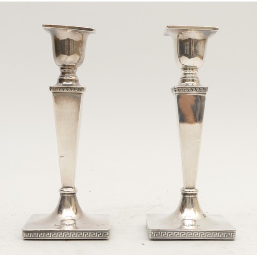 25 - A silver pair of desk candle sticks, by Walker & Hall, Sheffield 1918, Greek key bases, 16.5cm, load... 