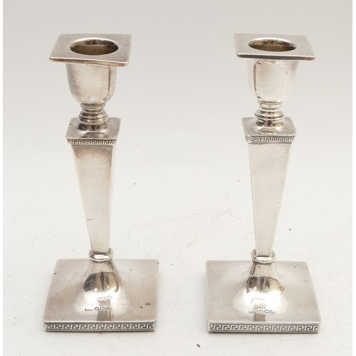 25 - A silver pair of desk candle sticks, by Walker & Hall, Sheffield 1918, Greek key bases, 16.5cm, load... 