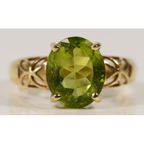 577 - A 9ct gold oval cut peridot dress ring with patterned shoulders, N, 3.4g